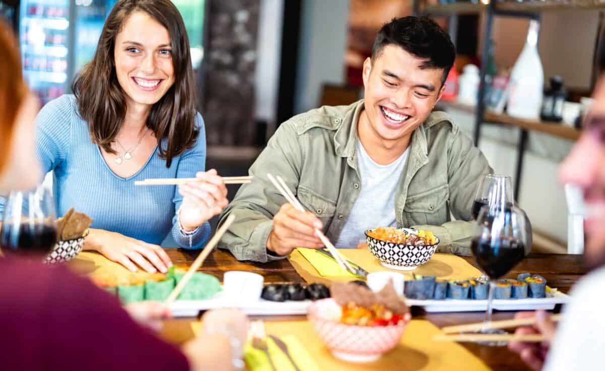 Amis multiculturels de la génération Z mangeant des sushis avec des baguettes dans un restaurant fusion winery