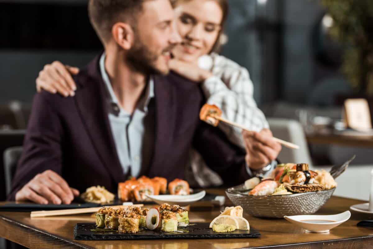 jeune couple souriant dînant et mangeant de délicieux rouleaux de sushi dans un restaurant
